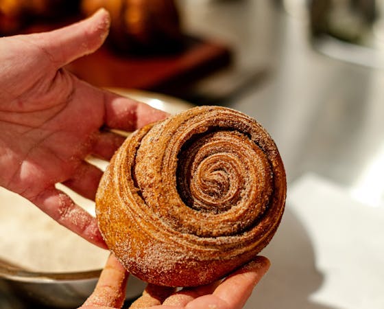 Image of two hands holding a cinnamon bun.