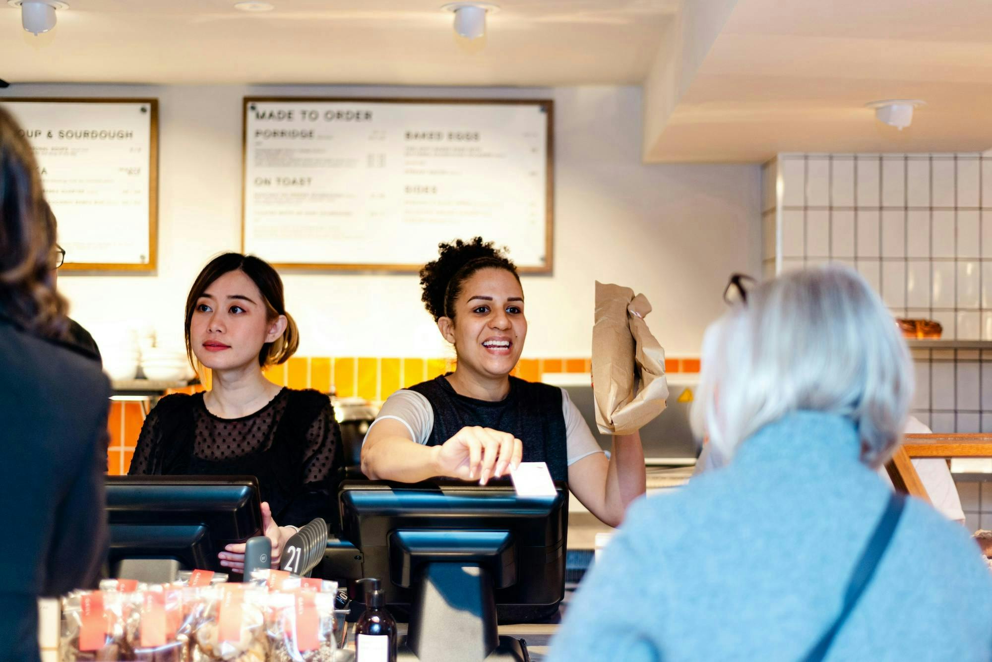 Two team members serving customers from behind a till