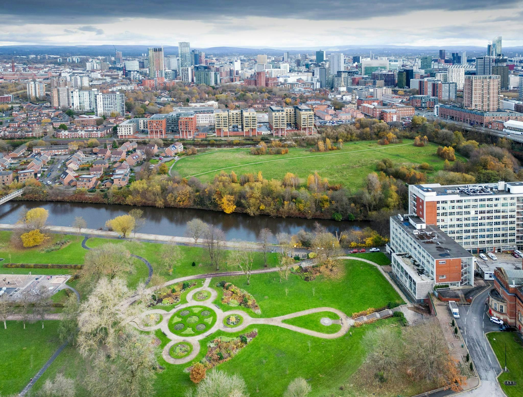 Aerial image of Salford with a green park in the foreground and buildings in the background.