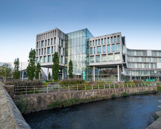 Image of a glass building in Rochdale with a river in the foreground