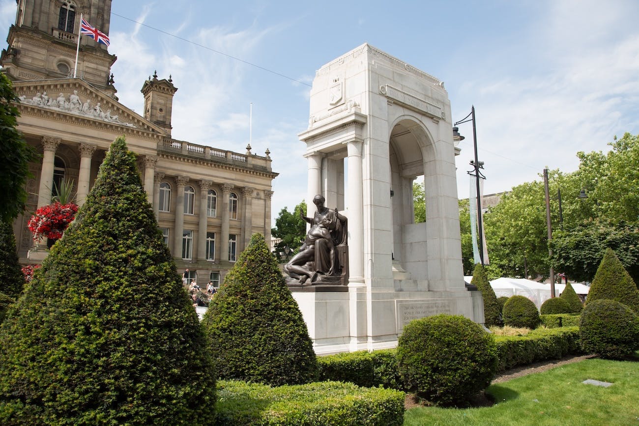Image of a cenotaph outside Bolton town hall surrounded by grass and hedges