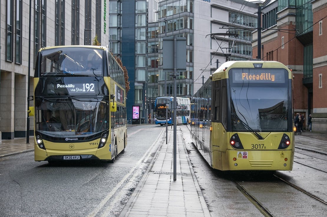 Image of a bus on the left and a tram on the right, all with 'Piccadilly' written on them. Another bus is visible in the background.