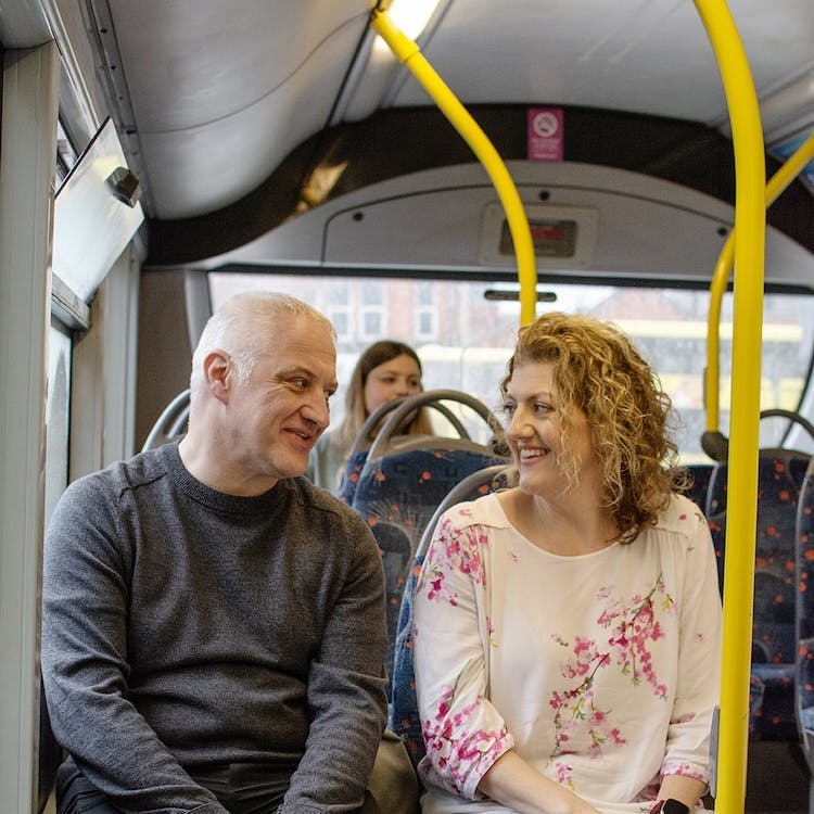 Two people looking at each other and smiling, sitting on the bus