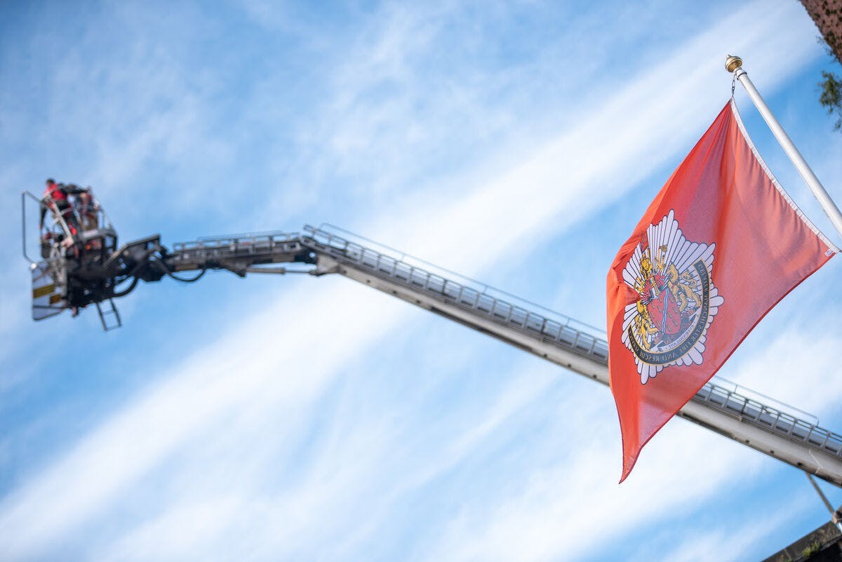 Image of a flag with a crane on the background and blue sky.