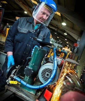 Image of a man wearing a suit and a protective helmet while engaging in some activity with a machine.