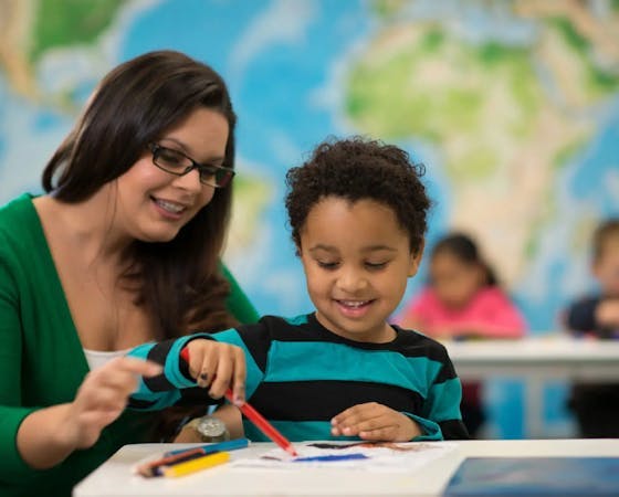 Image of a smiling lady and a child drawing together.