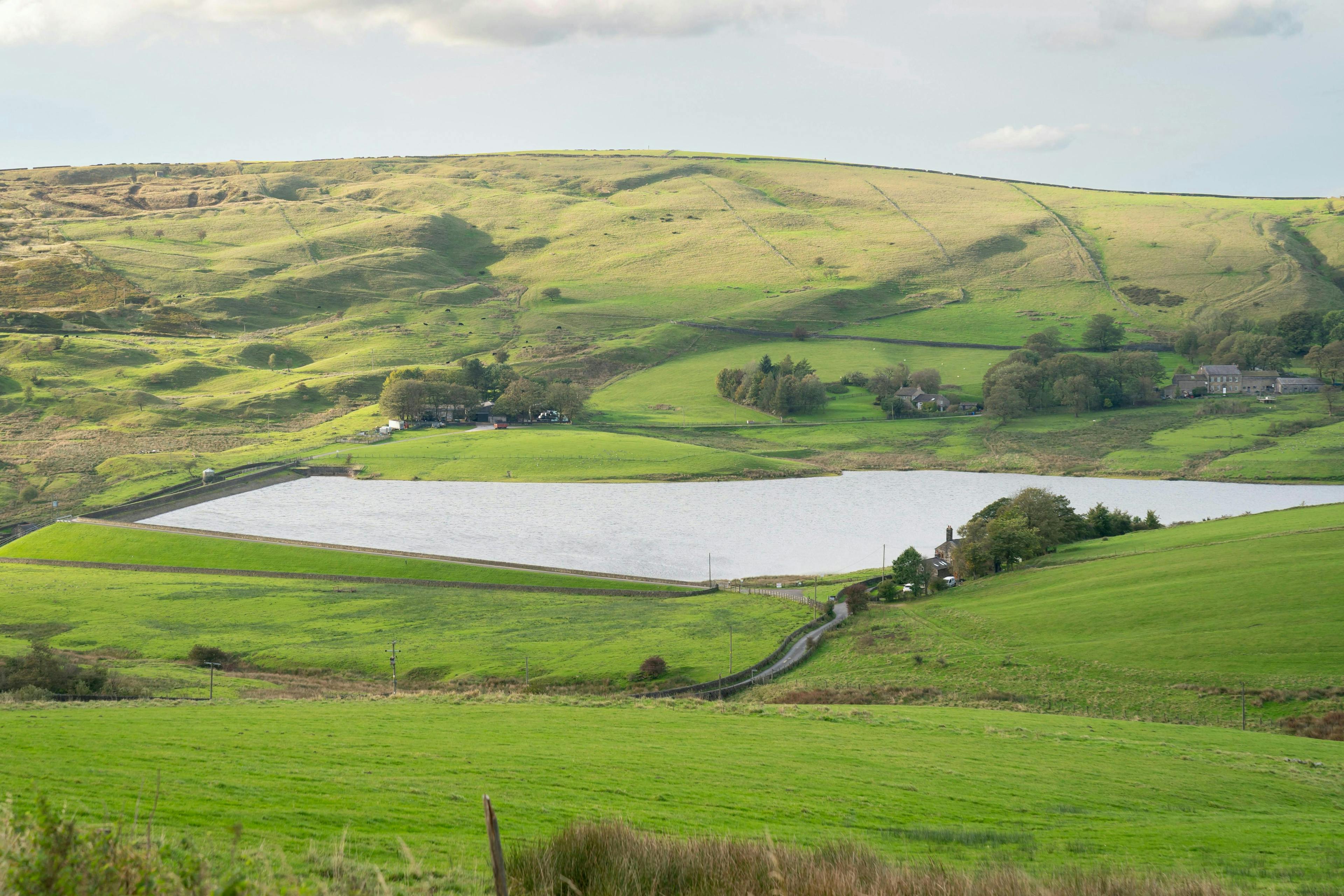 Image of a green hill with a lake in the middle, countryside in Oldham.